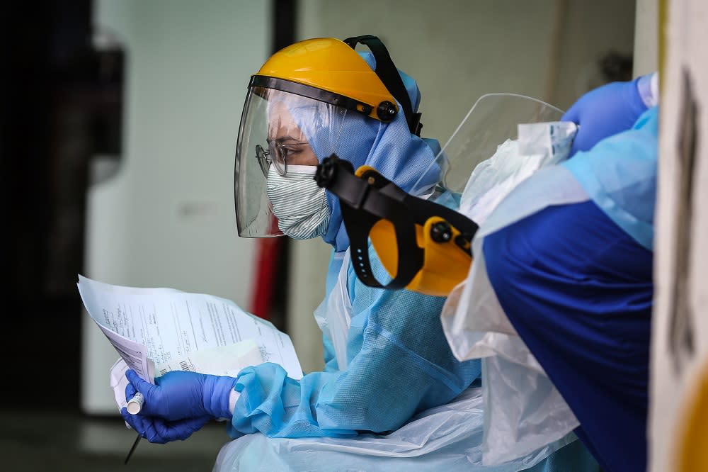 Health workers in protective suits are seen at a drive-through testing site for Covid-19 at KPJ Damansara Specialist Hospital in Petaling Jaya March 28, 2020. — Picture by Yusof Mat Isa