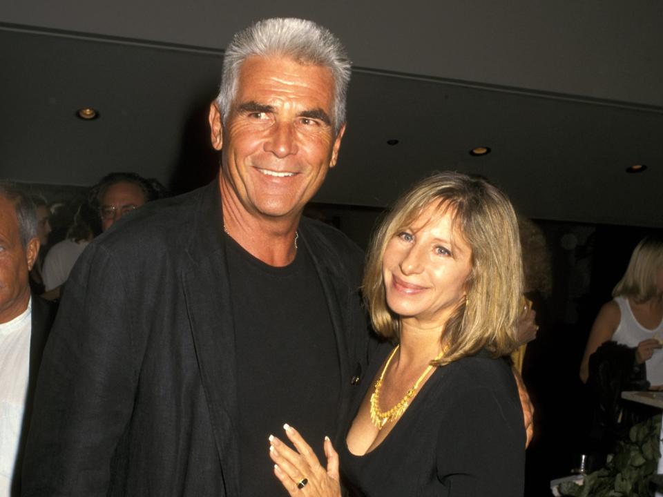 James Brolin, in a black shirt, black blazer, and jeans, poses with Barbra Streisand, in a black dress and gold necklace, at a 1997 event.