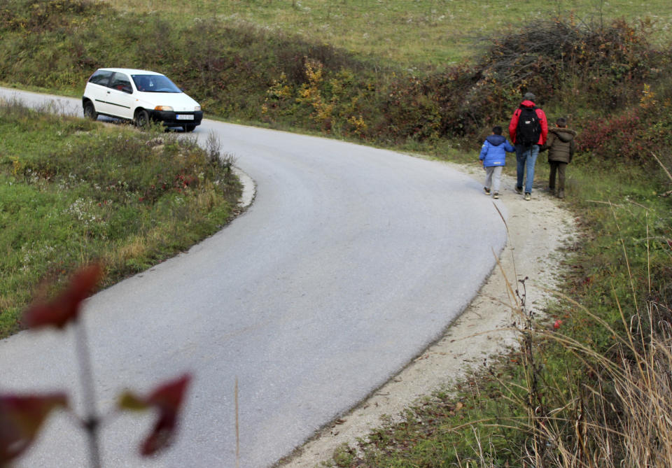 Ibrahim Rasool, Afghan refugee, formerly a FIFA-licensed futsal referee walks with children on the road near a makeshift camp housing migrants, in Velika Kladusa, Bosnia, Saturday, Nov. 13, 2021. Ibrahim Rasool loved his job as a futsal referee because of sportsmanship and fair play. But the 33-year-old man from Afghanistan says there is nothing fair about the way the European Union treats people seeking refuge from violence and war. (AP Photo/Edvin Zulic)