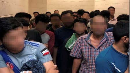 Men are crowded in a room at a Border Patrol station in a still image from video in McAllen