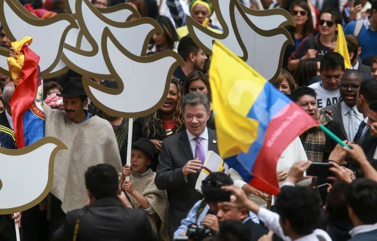 Colombian President Juan Manuel Santos (C) holds a copy with the final text of the peace agreement with the Revolutionary Armed Forces of Colombia (FARC) guerrillas, on his way to the National Congress in Bogota on August 25, 2016