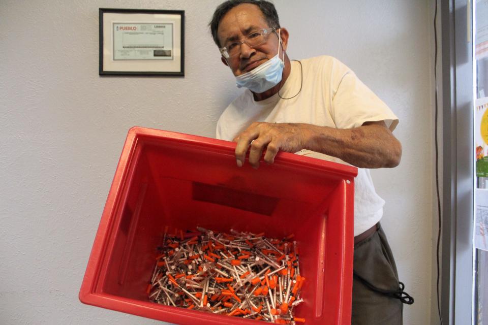 Frank Arteaga, a volunteer with the Southern Colorado Harm Reduction Association, holds up a container filled with needles turned into the organization as part of the its syringe access program.