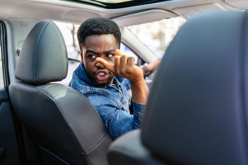 Man gesturing "call me" from the driver's seat of a car, looking back