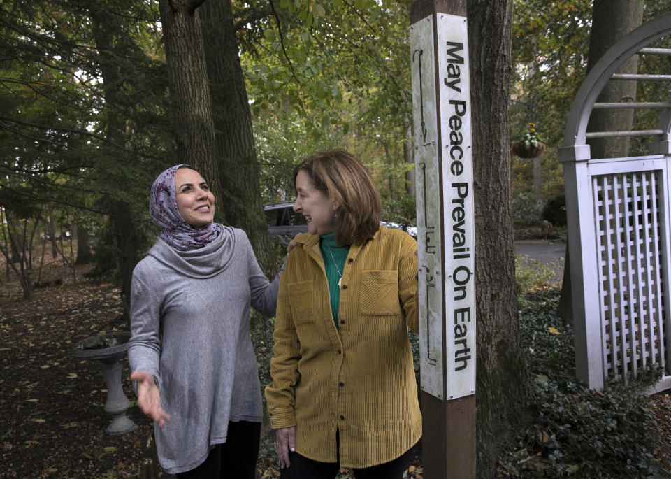 In this Thursday, Oct. 17, 2019, photo, Heba Macksoud, left, of Princeton, N.J., and Sheryl Olitzky, members of the Sisterhood of Salaam Shalom, stand near a Peace Pole written in English and Arabic, as they walk together at Olitzky's home, in North Brunswick, N.J. As the one-year anniversary of Pittsburgh's Tree of Life synagogue attack approaches, and an anti-Semitic shooting in Germany on the holiest day of the Jewish calendar focuses attention anew on the rising tide of global hate crimes against the faith, Jewish and Muslim groups in the U.S. are forging durable alliances in pushing back against crimes targeting their respective communities. (AP Photo/Mel Evans)