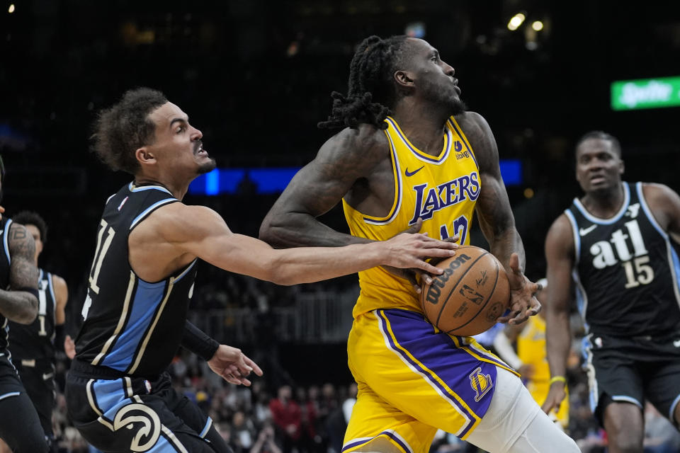 Los Angeles Lakers forward Taurean Prince (12) is fouled by Atlanta Hawks guard Trae Young (11) as he drives to the basket in the second half of an NBA basketball game Tuesday, Jan. 30, 2024, in Atlanta. (AP Photo/John Bazemore)