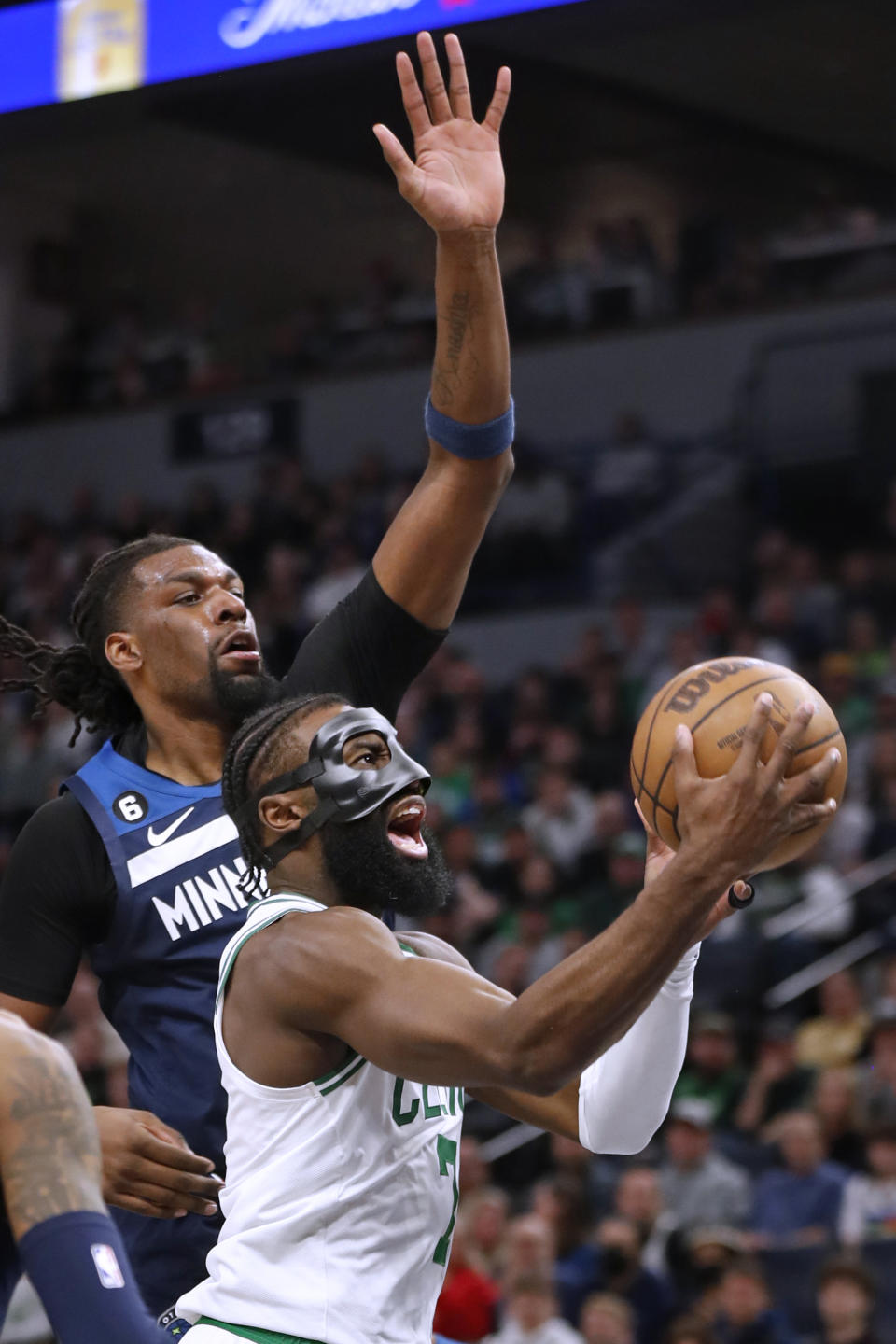 Boston Celtics forward Jaylen Brown, right, goes to the basket past Minnesota Timberwolves center Naz Reid, rear, during the fourth quarter of an NBA basketball game Wednesday, March 15, 2023, in Minneapolis. The Celtics won 104-102. (AP Photo/Bruce Kluckhohn)