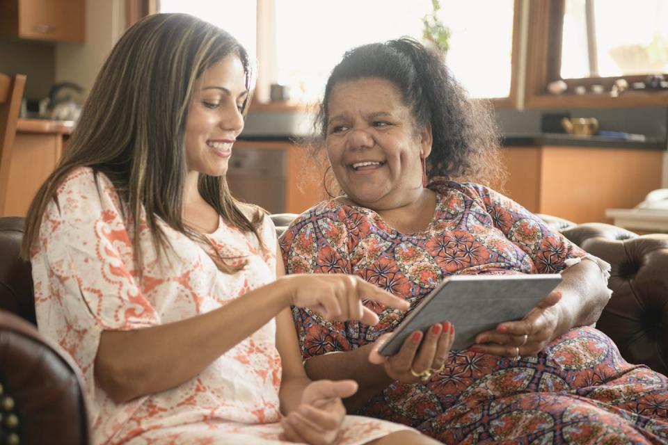 Two women smiling and using a tablet computer.