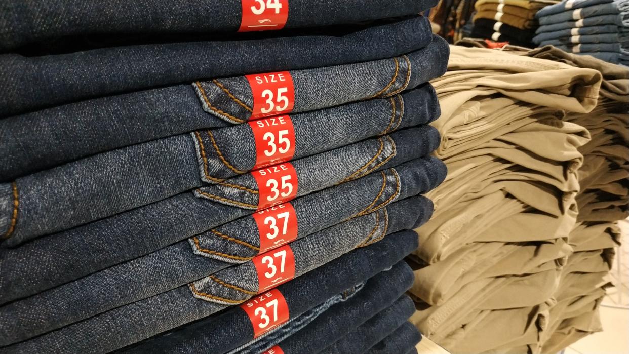 Closeup of a row of jeans hanging in a store. Narrow dof with focus on size tag