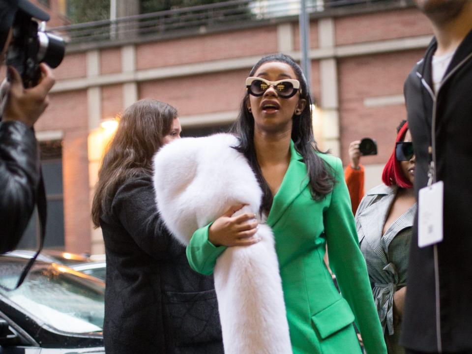 Cardi B is seen on the street attending Christian Siriano during New York Fashion Week wearing white fur and a green suit on February 10, 2018 in New York City.