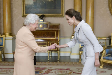 Actress Angelina Jolie is greeted by Britain's Queen Elizabeth before being presented with the Insignia of an Honorary Dame Grand Cross of the Most Distinguished Order of St Michael and St George, in the 1844 room at Buckingham Palace in London October 10, 2014. REUTERS/Anthony Devlin/pool