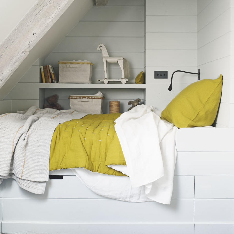 attic bedroom with white panelled walls and built in storage