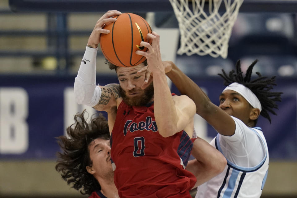 Saint Mary's guard Logan Johnson (0) hauls in a rebound over San Diego center Steven Jamerson II, right, and in front of Saint Mary's forward Kyle Bowen, left, during the first half of an NCAA college basketball game Thursday, Feb. 16, 2023, in San Diego. (AP Photo/Gregory Bull)