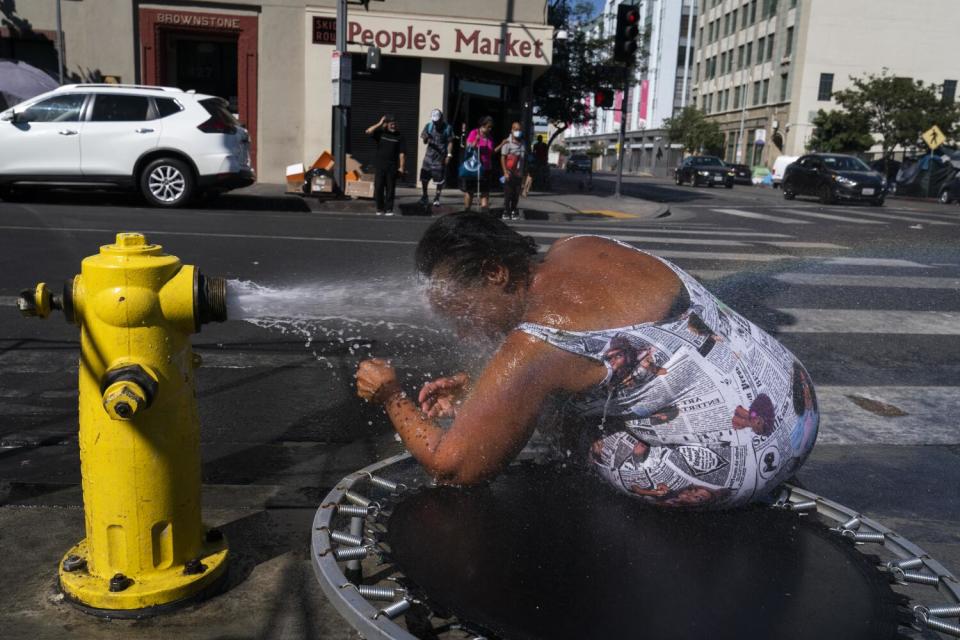 Stephanie Williams, 60, leans into a stream of water from a hydrant in the L.A.'s Skid Row on Aug. 31, 2022.