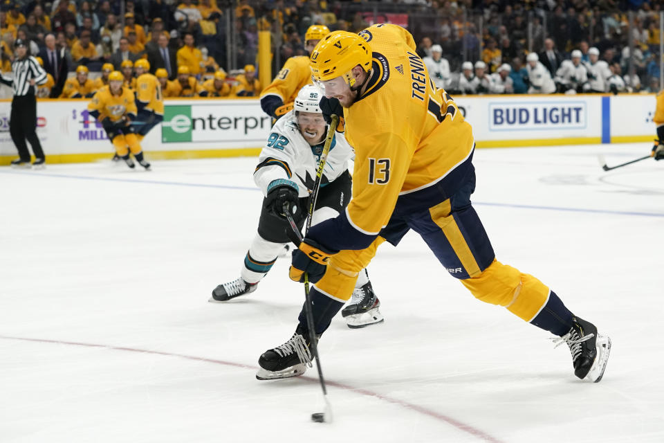 Nashville Predators center Yakov Trenin (13) shoots as San Jose Sharks left wing Rudolfs Balcers (92) reaches in during the second period of an NHL hockey game Tuesday, Oct. 26, 2021, in Nashville, Tenn. (AP Photo/Mark Humphrey)