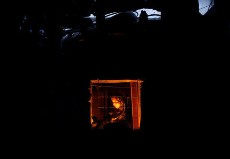 A Palestinian woman is seen from the window of her kitchen as she uses a candle light to prepare food during power cut in Beit Lahiya town in the northern Gaza Strip July 13, 2017. REUTERS/Mohammed Salem