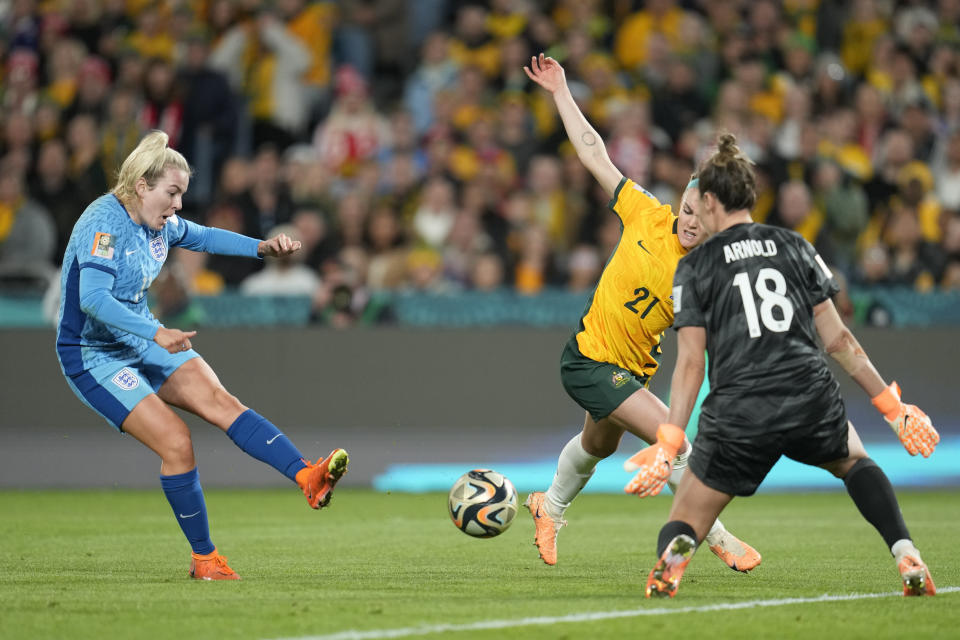 La inglesa Lauren Hemp (izquierda) anota el segundo gol de su equipo ante la arquera australiana Mackenzie Arnold, mientras la australiana Ellie Carpenter (centro) intenta bloquear el balón, en su semifinal del Mundial femenino de fútbol entre Australia e Inglaterra en el Estadio Australia de Sydney, Australia, el miércoles 16 de agosto de 2023. (AP Foto/Abbie Parr)