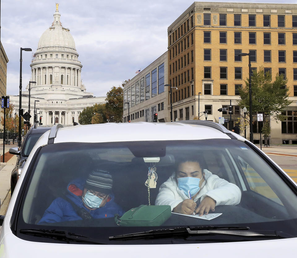 Madison, Wis. residents Evelio Mancera and his daughter, Jennifer Mancera, fill out their ballots on the first day of the state's in-person absentee voting window for the Nov. 3 election outside the city's City-County Building Tuesday, Oct. 20, 2020, in Madison, Wis. (John Hart/Wisconsin State Journal via AP)