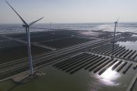 Wind turbines dot the coastline along a giant solar farm near Weifang in eastern China's Shandong province on March 22, 2024. Chinese battery companies, EV manufacturers and utilities are all racing to develop more advanced batteries to store the electricity from solar panels. (AP Photo/Ng Han Guan)