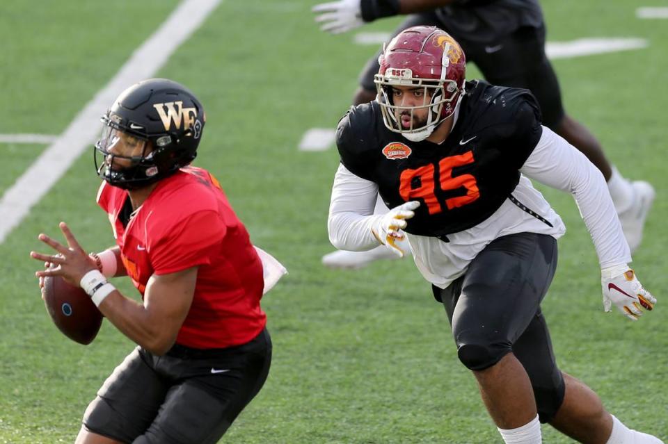 Defensive lineman Marlon Tuipulotu of USC (95) chases quarterback Jamie Newman of Wake Forest (7) during the American team practice for the NCAA college Senior Bowl in Mobile, Ala., Wednesday, Jan. 27, 2021. (AP Photo/Rusty Costanza)