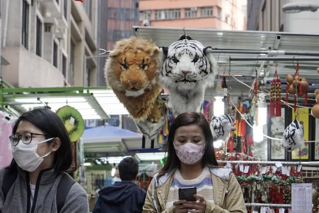 Women wearing masks, walk at a local market in Hong Kong