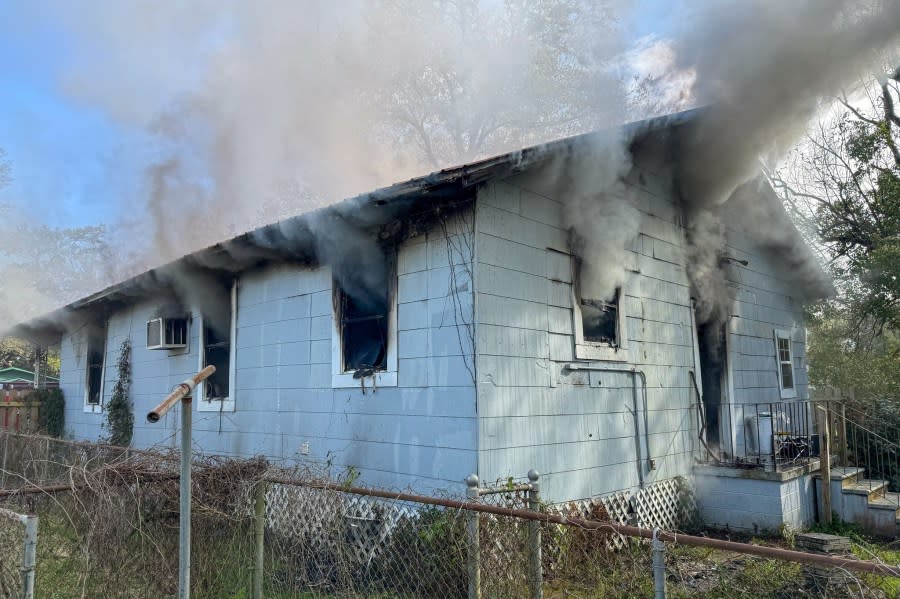 Photo of smoke coming out of the windows of a white, wooden house.