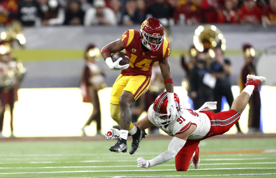 Southern California running back Raleek Brown (14) avoids a tackle attempt by Utah defensive end Gabe Reid (91) during the first half of the Pac-12 Conference championship NCAA college football game Friday, Dec. 2, 2022, in Las Vegas. (AP Photo/Steve Marcus)