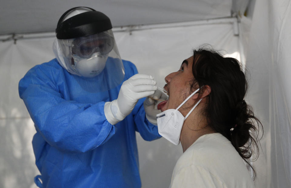 A healthcare worker collects a sample to test for the new coronavirus inside a mobile diagnostic tent, in the Coyoacan district of Mexico City, Friday, Nov. 13, 2020. Mexico City announced Friday it will order bars closed for two weeks after the number of people hospitalized for COVID-19 rose to levels not seen since August. (AP Photo/Eduardo Verdugo)