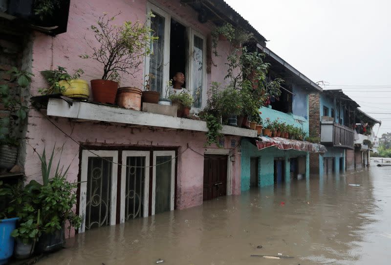 A man looks out from the window of his house in an area flooded by the overflowing Bagmati river following heavy rains, in Kathmandu