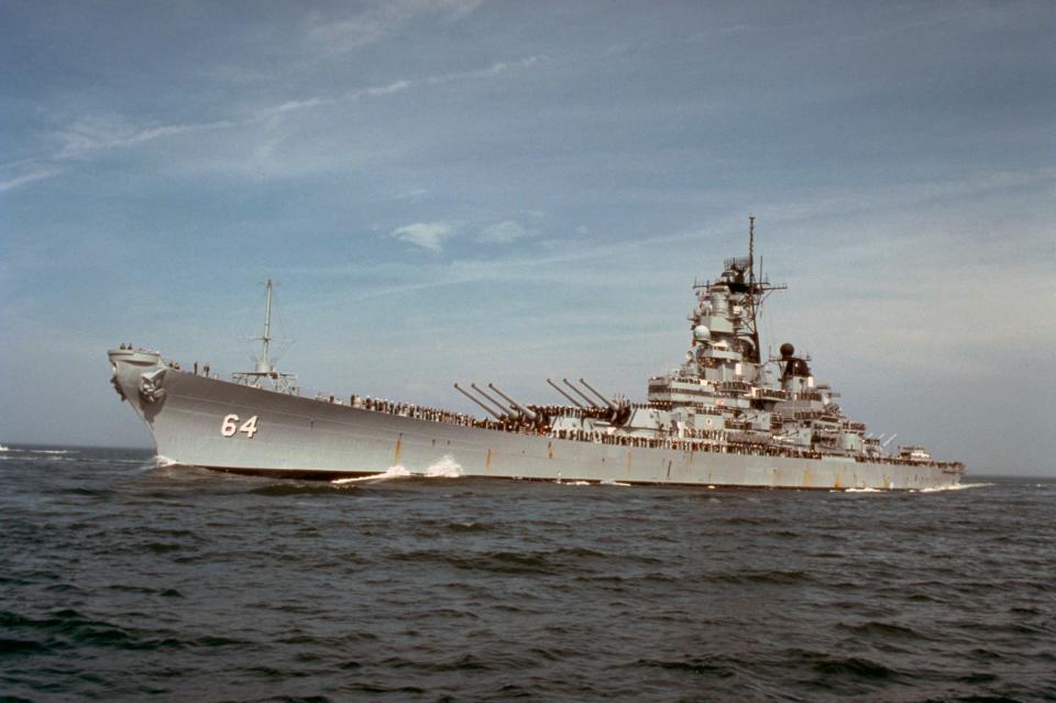 The battleship USS Wisconsin with sailors manning the rails as the vessel returns to port