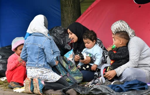 Migrant women with children sit outside their tent, in the park accross from the national ibrary in Sarajevo, on May 14, 2018