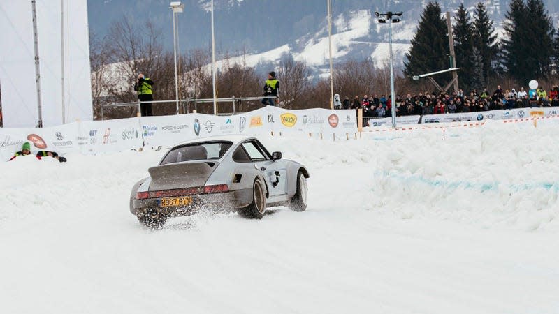 A Porsche 911 drifting around a corner on ice.