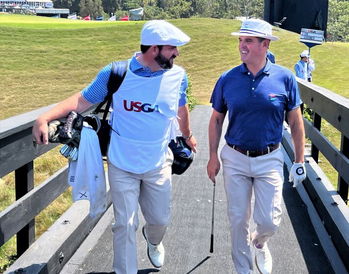 LACC director of golf Tom Gardner, right, walks across the bridge with Rory Sweeney, LACC's head pro and his caddie.