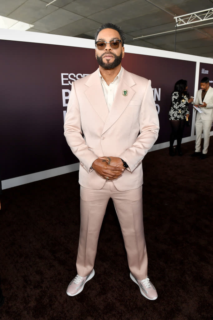 Method Man in a suit stands with hands clasped