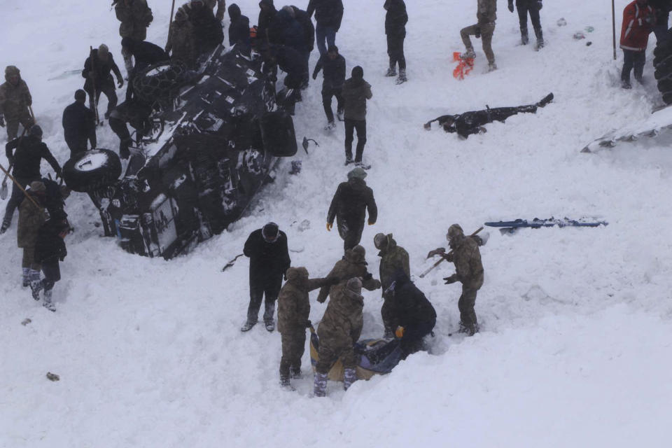 Emergency service members dig in the snow around at least three overturned vehicles, near the town of Bahcesehir, in Van province, eastern Turkey, Wednesday, Feb. 5, 2020. Some dozens of rescue workers are missing after being hit by an avalanche while on a mission to find two people missing in a previous snow slide. The emergency services were called to a highway in near the mountain-surrounded town in Van province, which borders Iran, after an avalanche struck late Tuesday, burying a snow-clearing vehicle and a minibus. (DHA via AP)