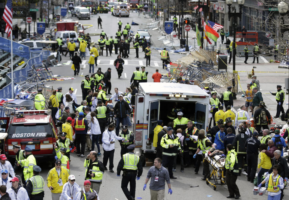 FILE — Medical workers aid injured people at the finish line of the Boston Marathon following an explosion in Boston, April 15, 2013. Two explosions shattered the euphoria of the finish line, sending authorities out on the course to carry off the injured while the stragglers were rerouted away from the smoking site of the blasts. In the decade since, the streets and sidewalks have been repaired, and a pair of memorials stand at the spot of the explosions to remember those who died: Martin Richard, Lu Lingzi and Krystle Campbell. (AP Photo/Charles Krupa, File)