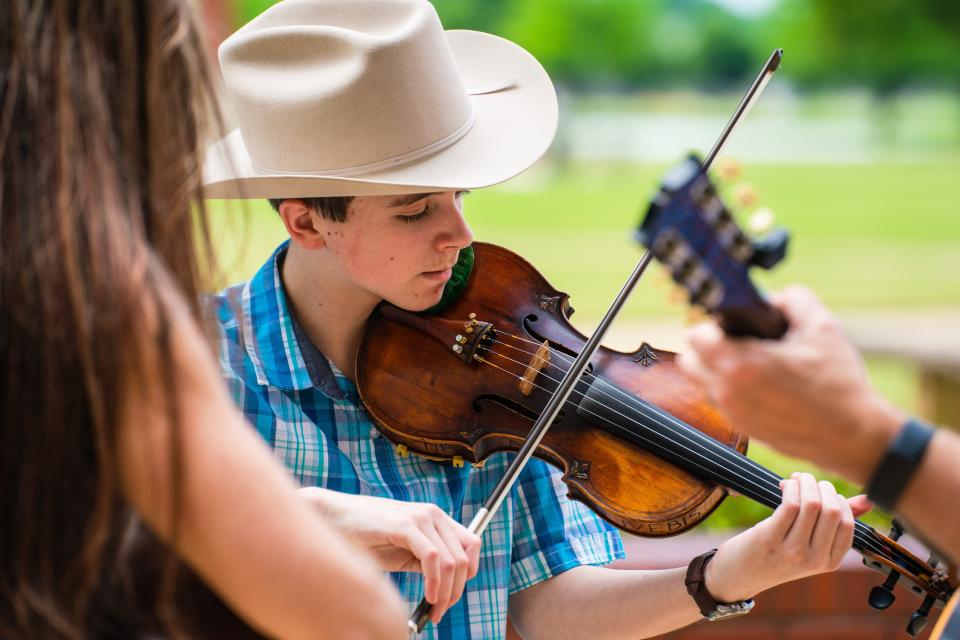 Fiddle player Noah Goeble jams in the court yard with guitarists Kerry Varble and Todd Varble after performing in the 2022 Fiddle Fest at Shelton State Community College, Saturday April 30, 2022. [Photo/Will McLelland]  