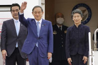 Japan’s Prime Minister Yoshihide Suga, second left, and his wife Mariko prepare to leave Haneda airport in Tokyo Sunday, Oct. 19, 2020. Suga left Sunday on his first overseas foray since taking over from his former boss Shinzo Abe last month, heading to Vietnam and Indonesia. (Shigeyuki Inakuma/Kyodo News via AP)