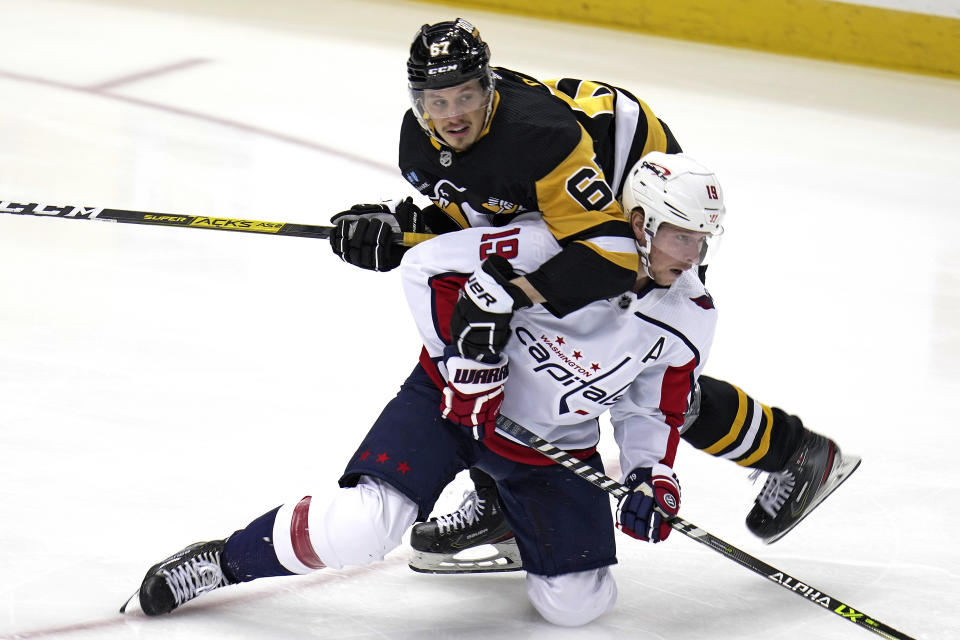 Pittsburgh Penguins' Rickard Rakell (67) and Washington Capitals' Nicklas Backstrom (19) collide during the first period of an NHL hockey game in Pittsburgh, Saturday, March 25, 2023. (AP Photo/Gene J. Puskar)