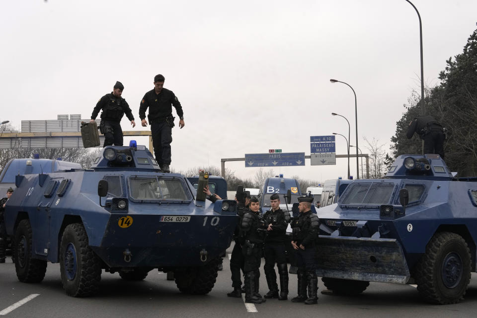 French gendarmes stand by their military vehicles on a blocked highway, preventing farmers to enter Paris, Wednesday, Jan. 31, 2024 in Chilly-Mazarin, south of Paris. Farmers have captured France's attention by showering government offices with manure and besieging Paris with traffic-snarling barricades of tractors and hay bales. Protesters say it's becoming harder than ever to make a decent living from their fields, greenhouses and herds. (AP Photo/Thibault Camus)