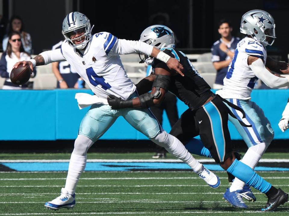 Dallas Cowboys quarterback Dak Prescott, left, fights to stay on his feet as Carolina Panthers linebacker Brian Burns, right, looks to make the sack during first-quarter action at Bank of America Stadium in Charlotte, NC on Sunday, November 19, 2023.