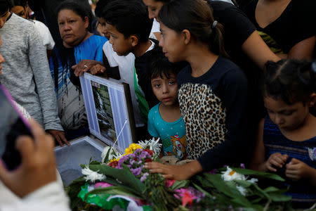 People stand next to the coffin of Saylin, 14, who, according to the police, was killed by Barrio-18 gang members, during her funeral, in Tegucigalpa, Honduras, July 19, 2018. According to police authorities, Saylin was kidnapped and tortured by her killers. REUTERS/Edgard Garrido