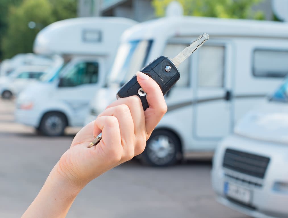 Woman's hand with key against campervans background.