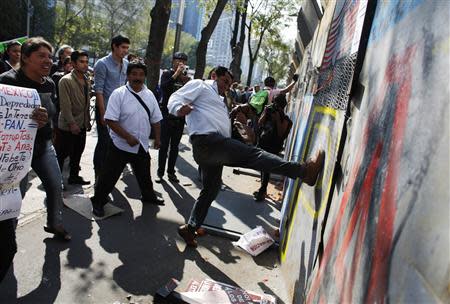 Protesters kick a barricade surrounding the senate building in Mexico City December 9, 2013. REUTERS/Tomas Bravo