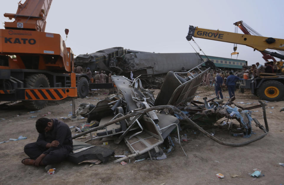 Soldiers and railway workers use crane to clear the track at the track at the site of a train collision in the Ghotki district, southern Pakistan, Monday, June 7, 2021. An express train barreled into another that had derailed in Pakistan before dawn Monday, killing dozens of passengers, authorities said. More than 100 were injured, and rescuers and villagers worked throughout the day to search crumpled cars for survivors and the dead. (AP Photo/Fareed Khan)