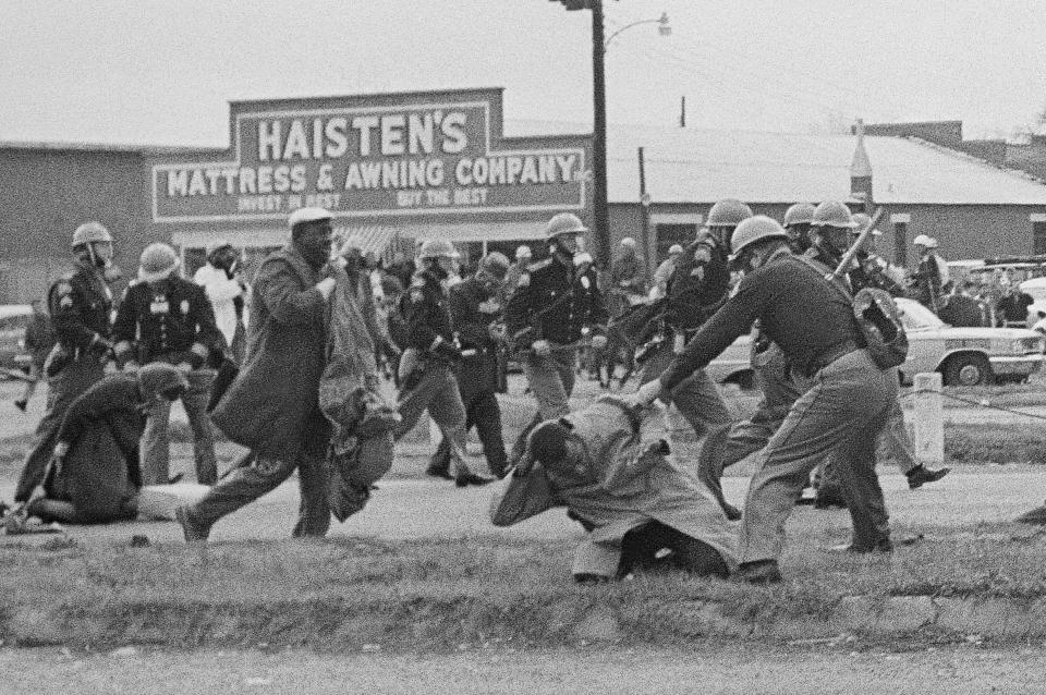 In this March 7, 1965, file photo, a state trooper swings a billy club at John Lewis, right foreground, chairman of the Student Nonviolent Coordinating Committee, to break up a civil rights voting march in Selma, Ala. 