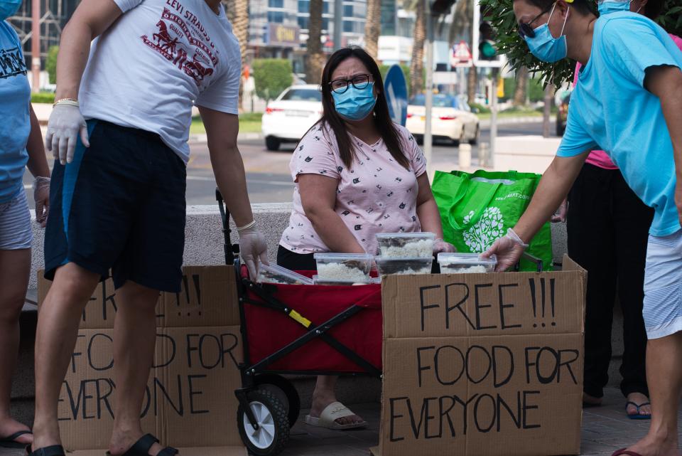 In this Wednesday, June 3, 2020 photo, Feby Cachero Baguisa Dela Pena of Laguna, Philippines, hands out free food to those who need it in Dubai, United Arab Emirates. Dela Pena, a mother of three, is unemployed, but when she saw people lining up for free meals one night outside her building two weeks ago she decided to use whatever money her family had to help out the countless numbers of Filipinos and others who've lost jobs amid the coronavirus. (AP Photo/Jon Gambrell)