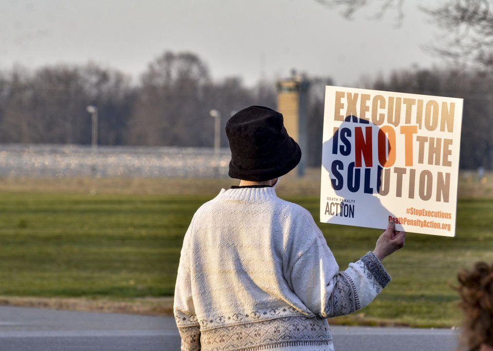 A protester holds an anti death penalty sign along Prairieton Road across from the Federal Execution Chamber Thursday, Dec. 10, 2020 in Terre Haute, Ind. The execution Brandon Bernard, convicted in the 1999 killing of two youth ministers in Texas is scheduled Thursday at the federal prison in Terre Haute, Indiana.. (Austen Leake/The Tribune-Star via AP)