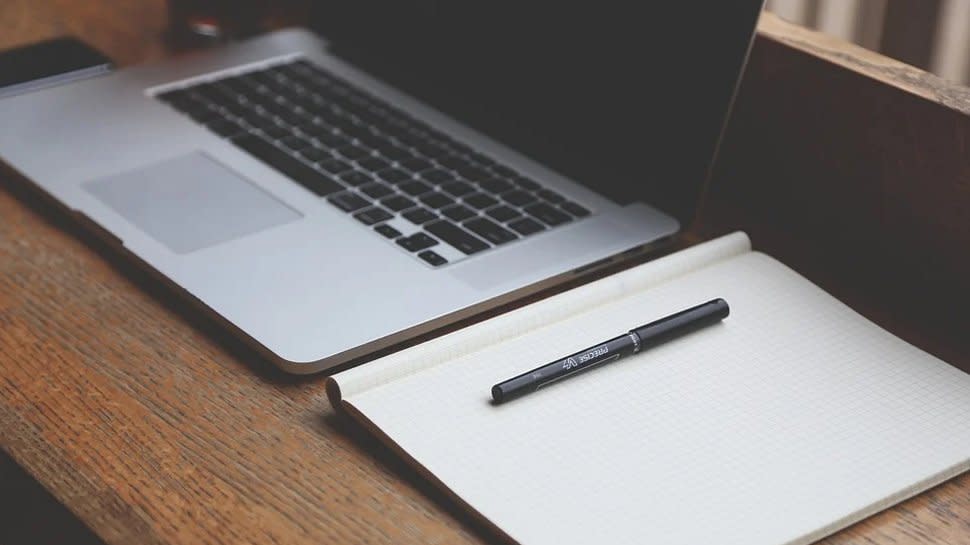  A pen and notepad next to a laptop. 