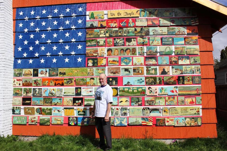 In this photo taken April, 2013, resident Richard Ormbrek stands next to his house, which has been decorated with a 20-foot wide American flag made up of 180 individually-painted tiles, in Seattle. (AP Photo/Cedar Burnett)