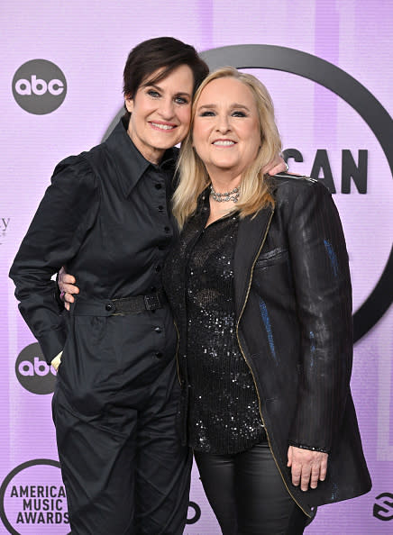 Linda Wallem and Melissa Etheridge pose together at the American Music Awards, both dressed in black outfits. 